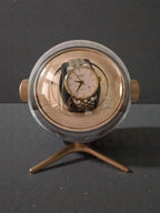 Vintage watch inside a round, metallic display case on a dark background