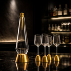Clear bottle with gold cap and base, accompanied by four matching glasses on a dark surface.