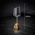 Clear wine glass with gold base on a dark surface, showing measurements.
