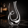 Clear glass decanter on a dark marble surface with a blurred bar background