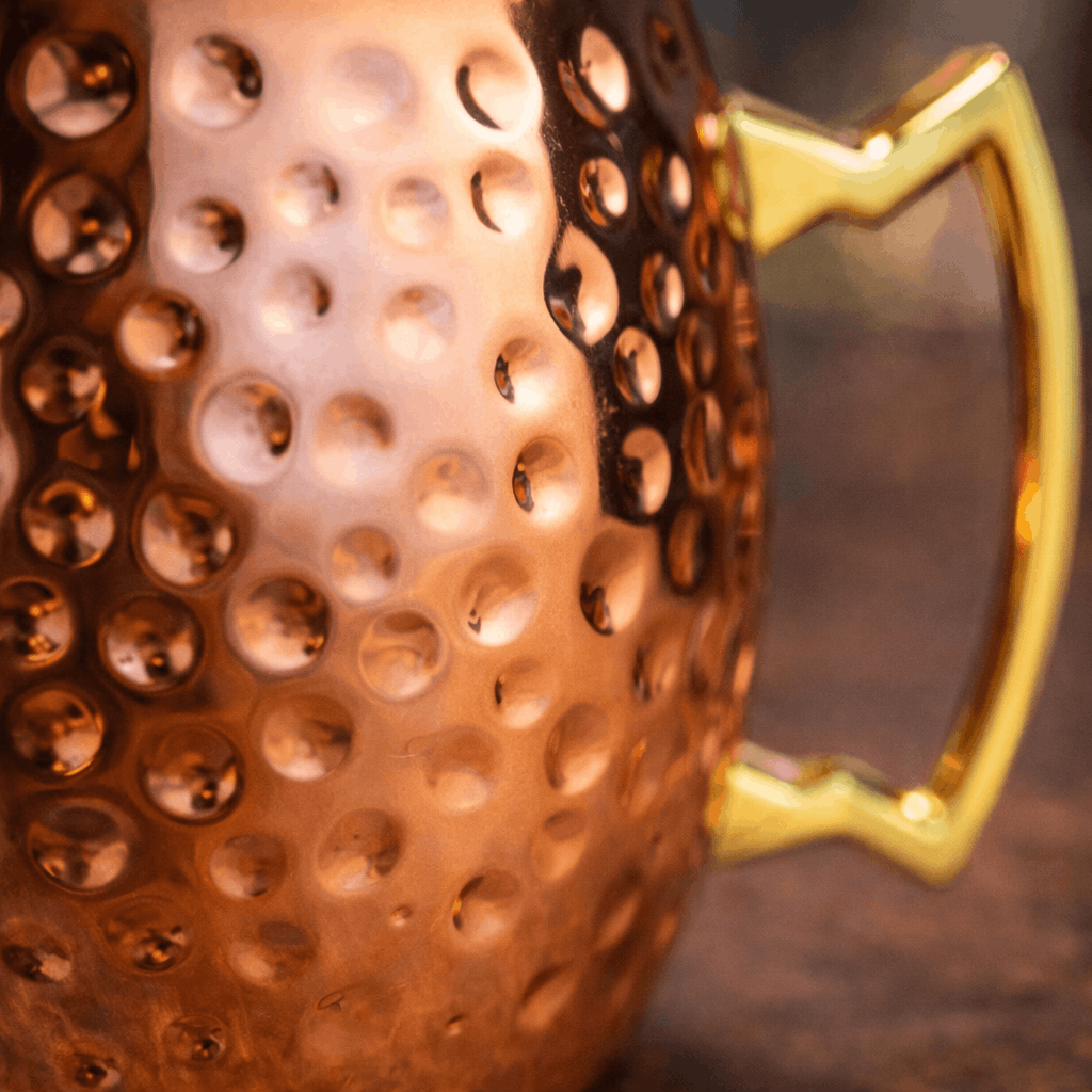 Close-up of a copper-colored grater with a gold handle on a dark background