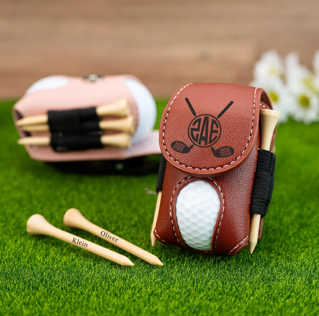 Brown leather golf tees case with golf ball and tees on grass