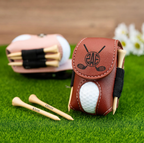 Brown leather golf tees case with golf ball and tees on grass