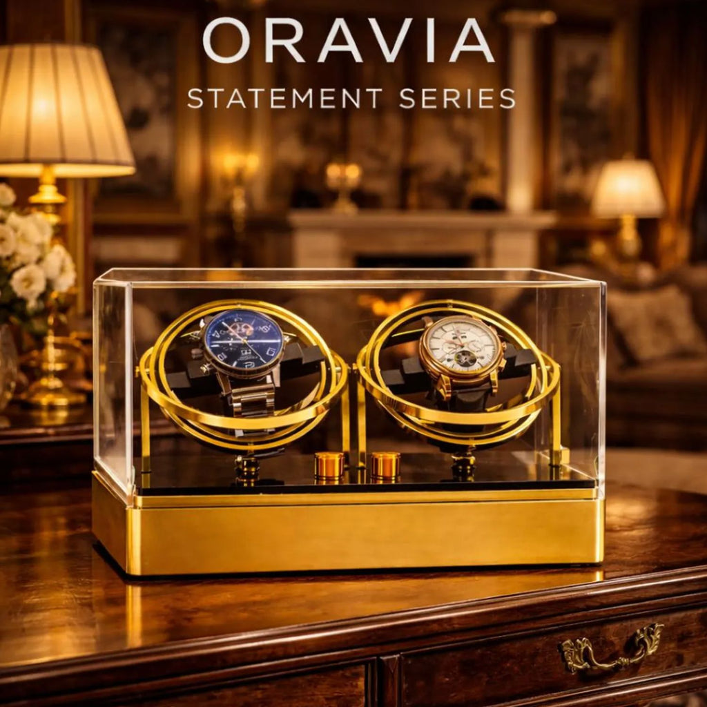 Two watches in a gold and clear display case with 'ORAVIA' branding in an elegant room.
