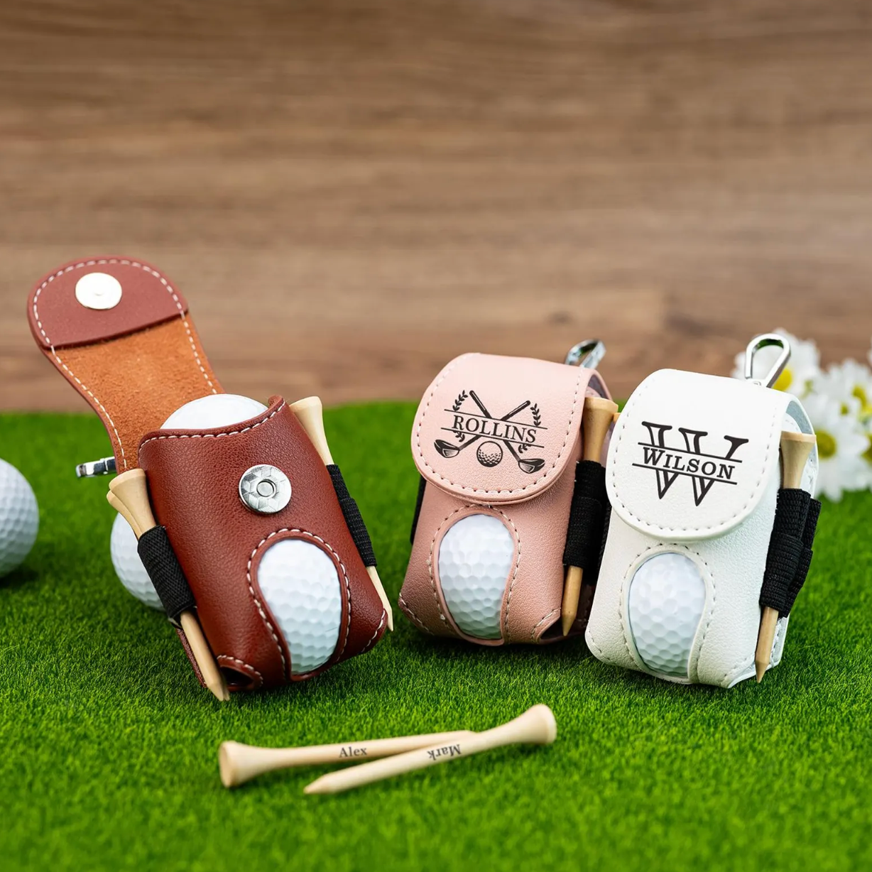 Three golf ball protectors with visible branding on a grassy surface.