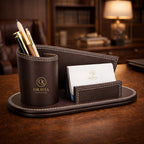 Brown leather desk organizer with pen holder and business card holder on a wooden desk.