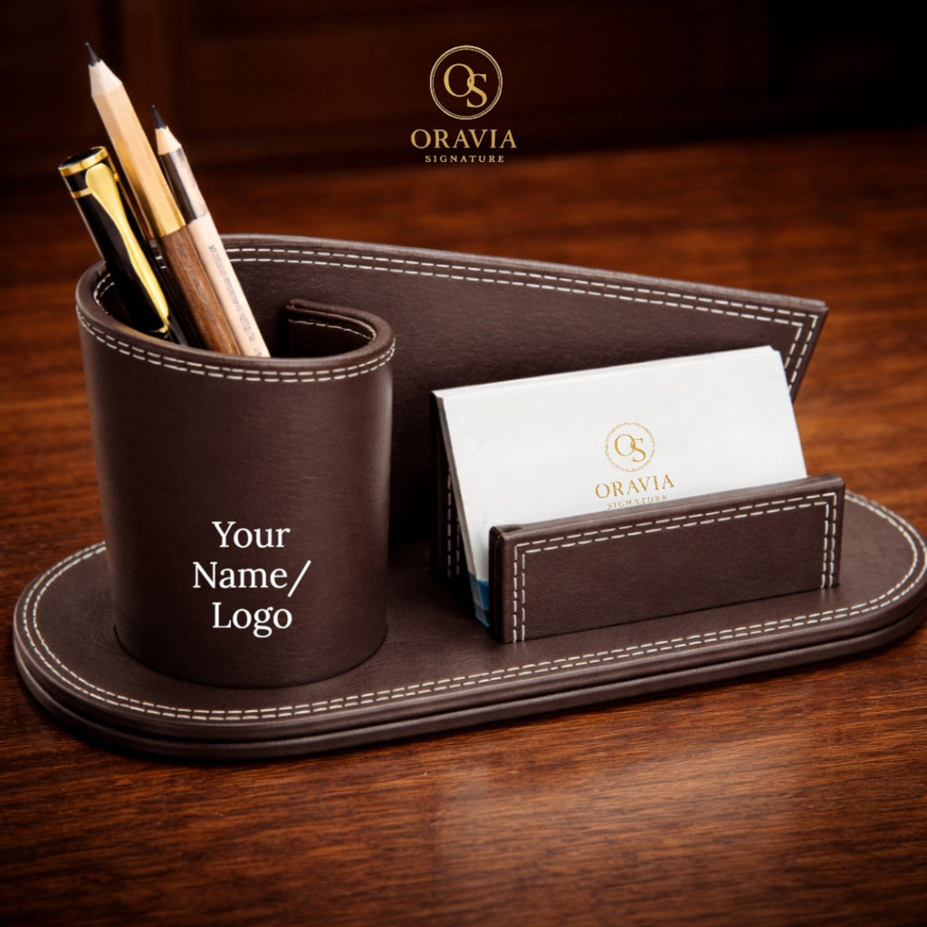 Brown leather desk organizer with pen holder and business card holder on a wooden surface, featuring the Oravia brand.