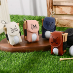 Four golf ball holders with monograms on a wooden stand outdoors.