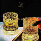 Two illuminated glass candle holders with intricate designs on a dark background, featuring the Oravia brand.