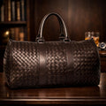 Woven leather duffel bag on a wooden surface with a blurred background