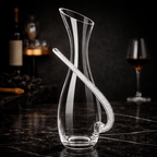 Clear glass decanter with a long handle on a dark marble surface.