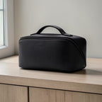 Black leather toiletry bag on a wooden surface with a neutral background