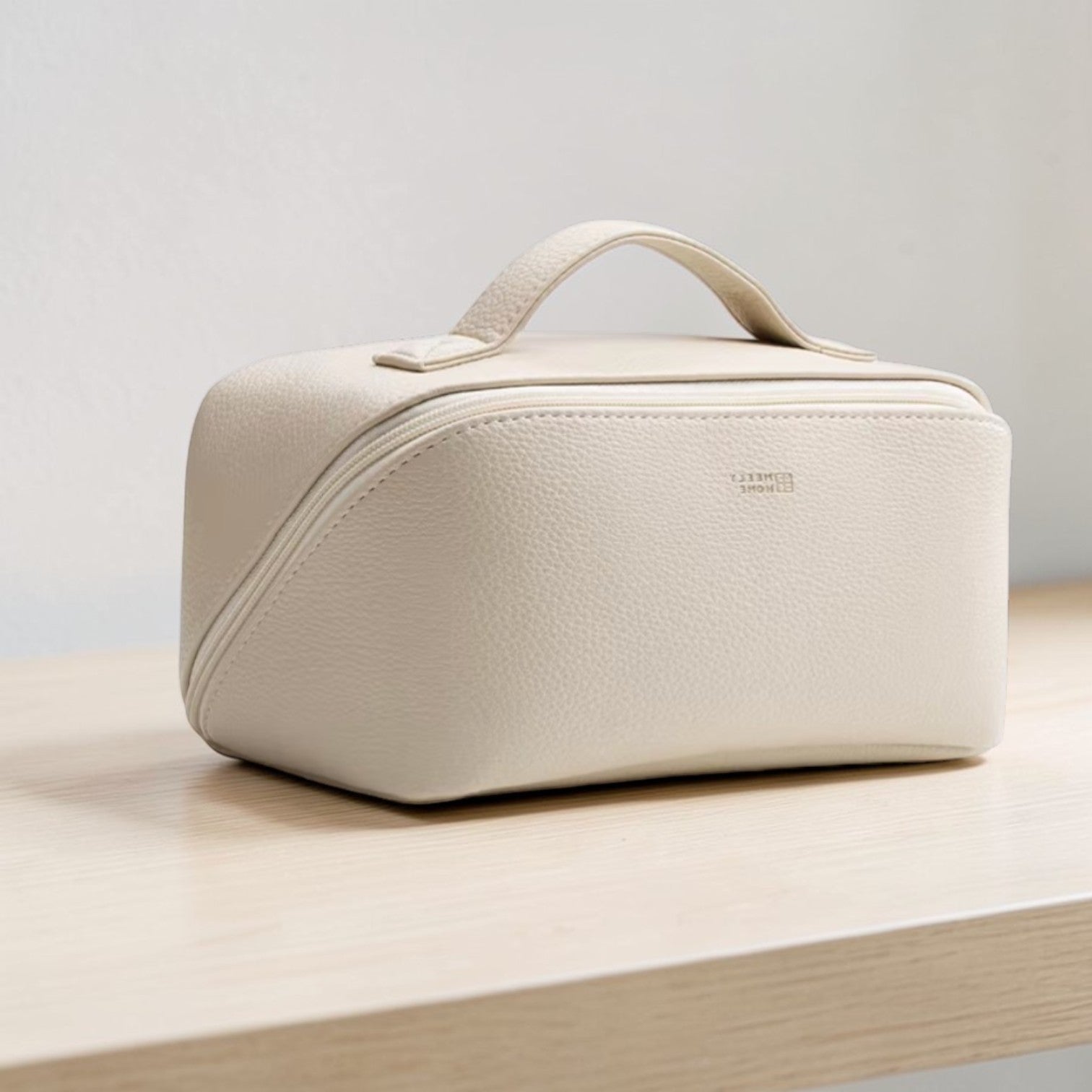 Beige toiletry bag on a wooden surface with a light gray background
