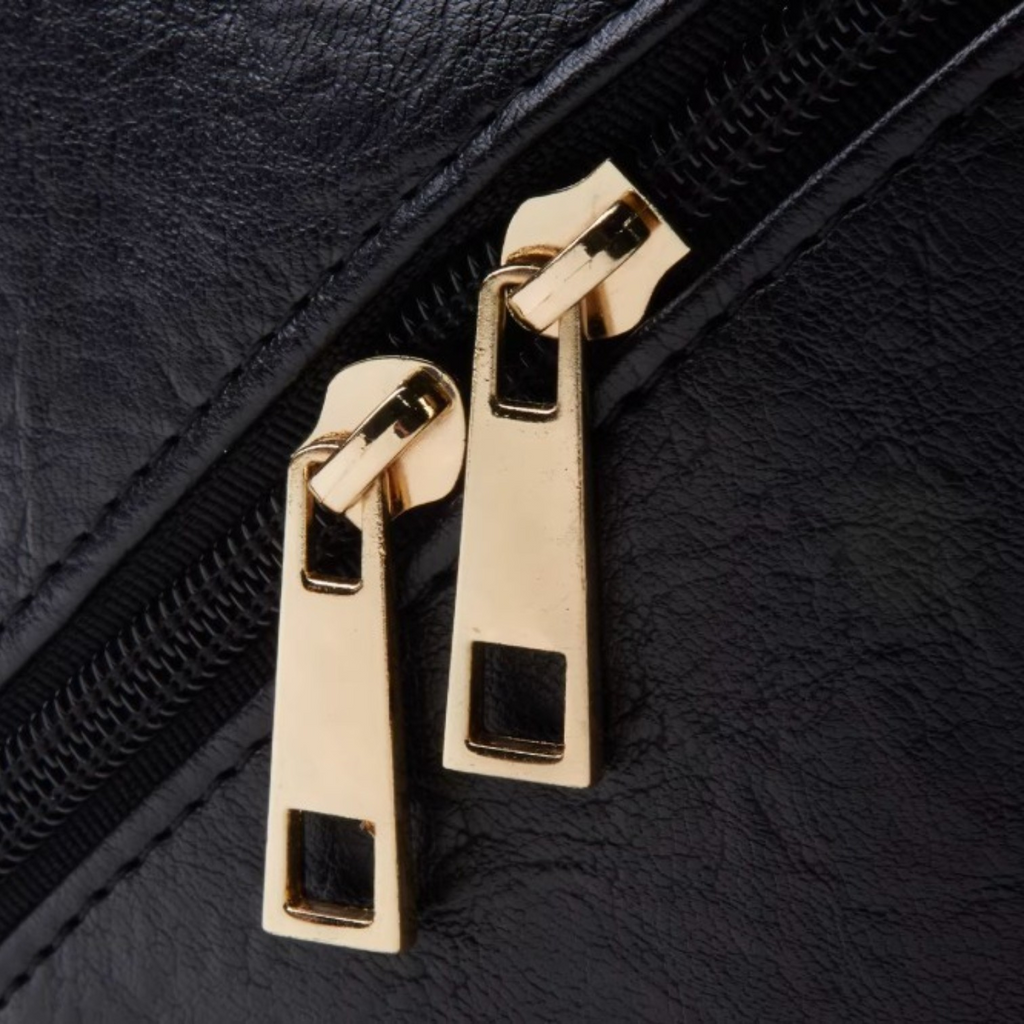 Close-up of gold zipper pulls on a black leather surface