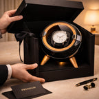 Watch in a black winder box with a bow, on a table with a card labeled 'Premium'.