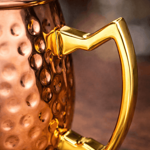 Close-up of a copper mug with a gold handle on a blurred background