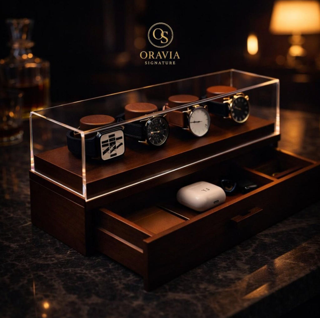 Wooden watch display case with watches on a dark background, featuring the Oravia Signature logo.