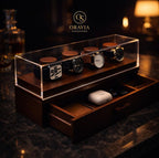 Wooden watch display case with watches on a dark background, featuring the Oravia Signature logo.