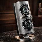 Silver watch winder with two watches on a dark surface