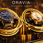Two gold watches on a decorative stand with 'ORAVIA' branding.watch winder 