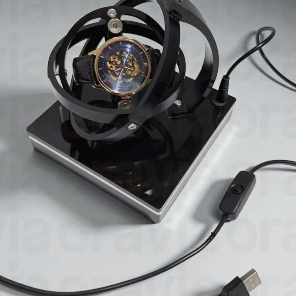 Watch winder  in a black metal stand with USB cable on a light gray background
