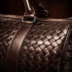 Close-up of a brown woven leather bag with a dark background
